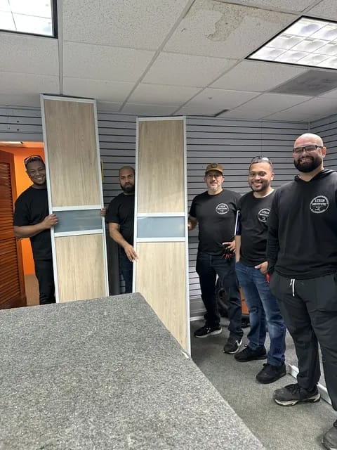 Grupo de estudiantes junto a las puertas de aluminio que construyeron.